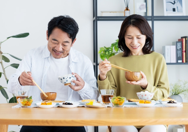 しっかり噛んで食事を楽しむ夫婦の画像