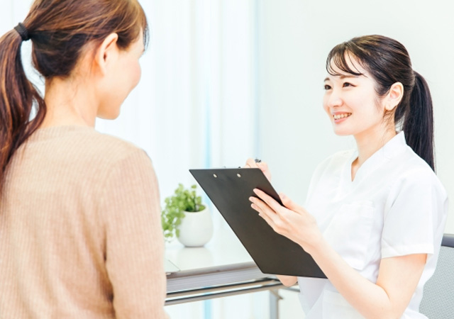 歯科で女性医療スタッフが患者さんにインプラントについてヒアリングしている様子