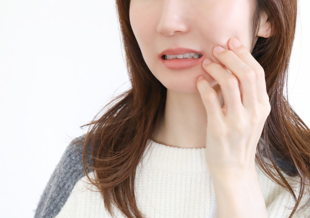 インプラント治療後の歯の痛みを気にする女性の画像