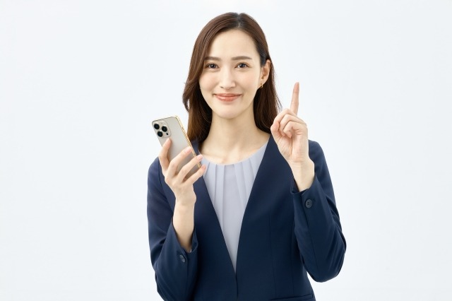 スマホを持ちながら指さししている女性
