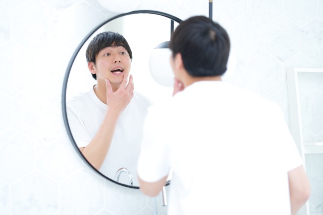 鏡で口の中を確認する男性